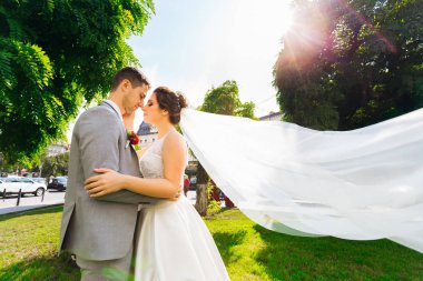 Yeni evliler gözlerini kapatıp sarıldılar. ağaçlar ve yeşil çim  