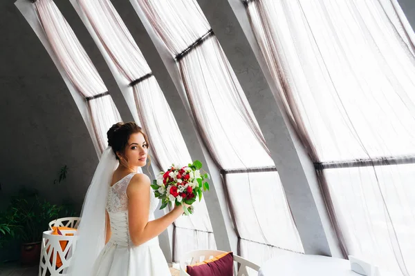 Noiva elegante detém um buquê de casamento no salão de restaurante nea — Fotografia de Stock