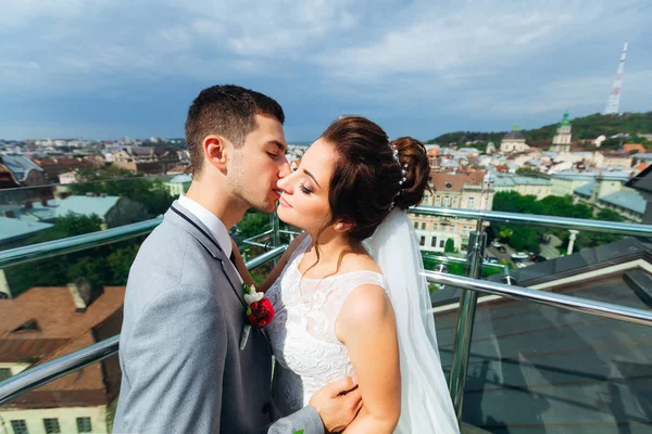 Frischvermählte küssen sich auf dem Balkon mit herrlichem Blick auf die Stadt — Stockfoto