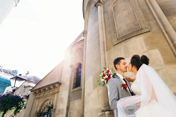 Brudgummen omfamnar och kysser bruden mot bakgrund av — Stockfoto
