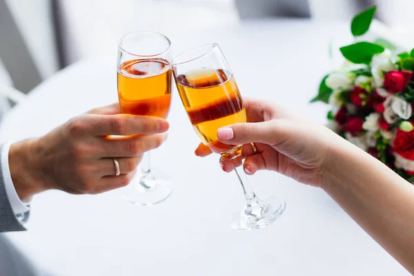 Occhiali da vino di champagne in mani di persone appena sposate. anello sul ring — Foto Stock