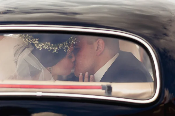 新婚夫妇在车里接吻。这对新婚夫妇是显而易见的 — 图库照片