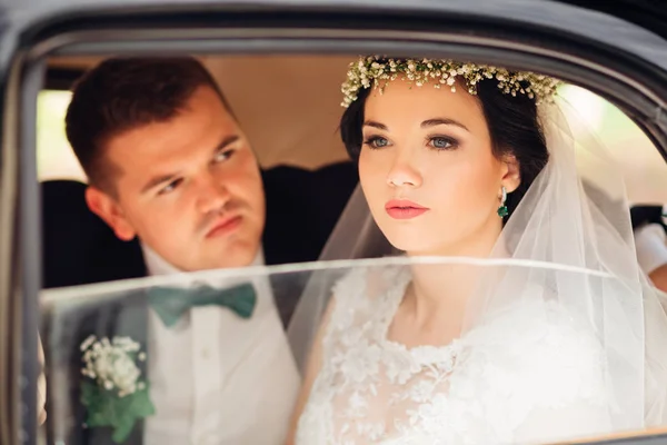 De mooie bruid zit in de auto en kijkt door th — Stockfoto