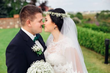 yeni evliler kucaklaşır ve öpüşmek isterler. Gelin düğün bouque tutan