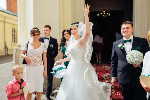 Novia sosteniendo una cesta y lanzando caramelos. recién casados e invitados —  Fotos de Stock