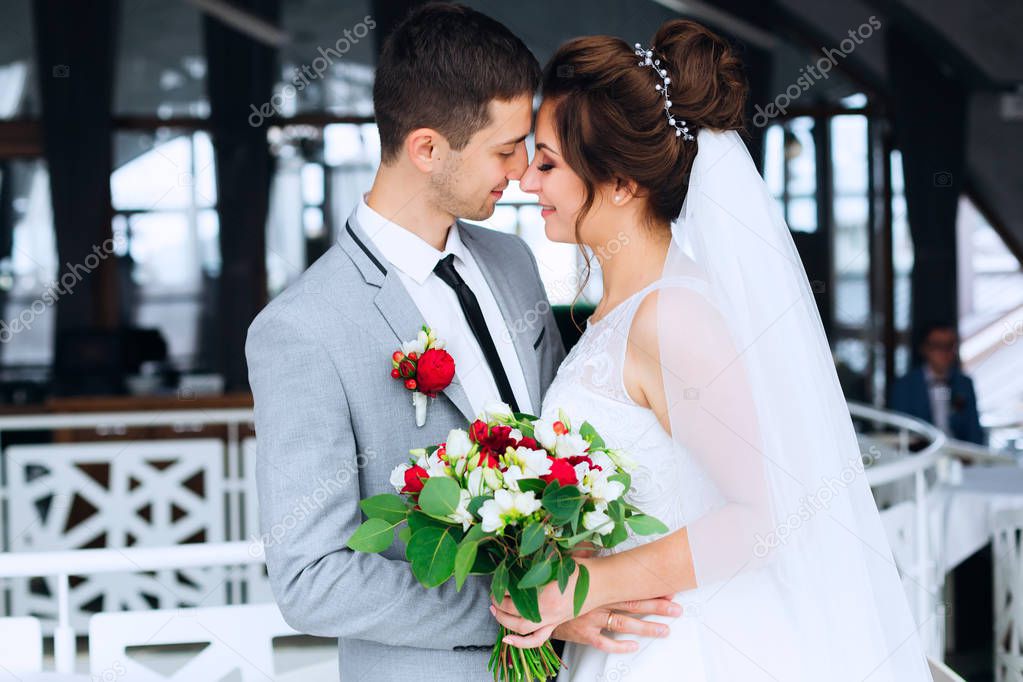the newlyweds kiss in the restaurant hall. The bride hold a wedd