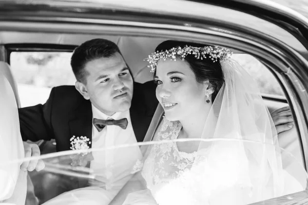 穿着节日服装的新婚夫妇坐在车里，看着对方 — 图库照片
