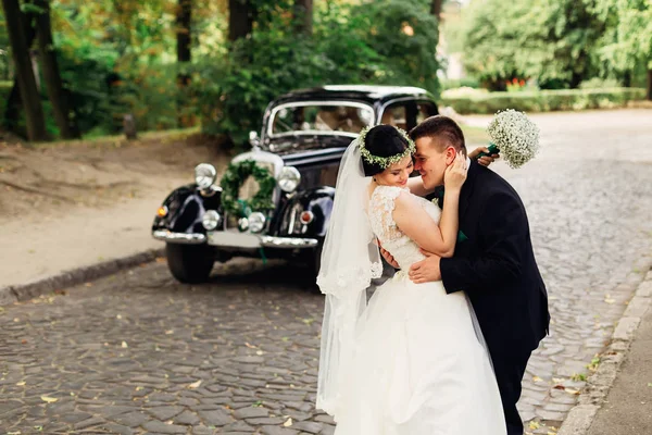 Gelin bir düğün buketi tutar ve damat onu kucaklar — Stok fotoğraf