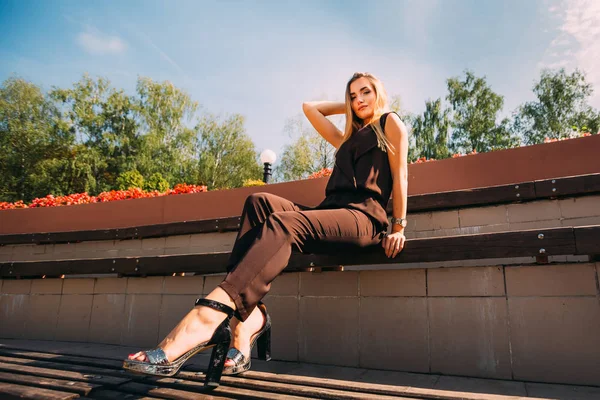 Stylish girl posing and looking into the camera. bench in the pa — Zdjęcie stockowe