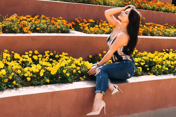 Una chica elegante se sienta en el macizo de flores y cierra los ojos. profi — Foto de Stock