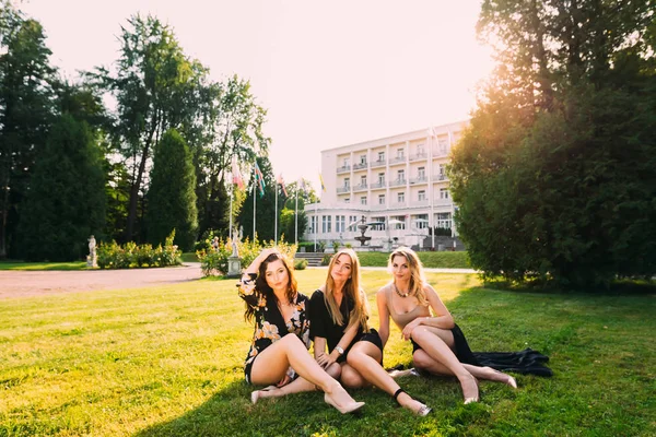 Vackra flickor sitter på gräset och tittar på kameran — Stockfoto