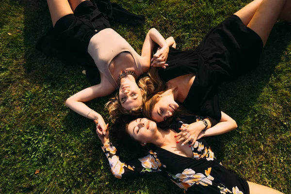 Дівчата лежать на траві з закритими очима і тримати руки — стокове фото