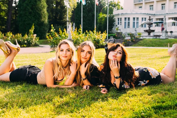 Las chicas se acuestan en la hierba y miran la cámara en el backgro — Foto de Stock