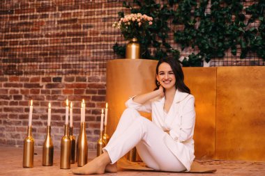 Beyaz takım elbiseli bir kadın yerde oturur ve içine bakarak