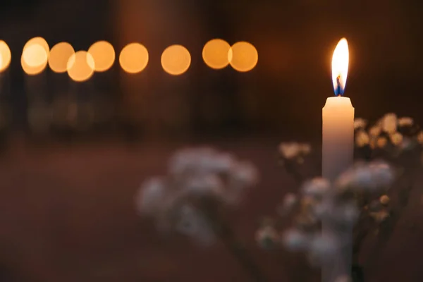 Close-up of a candle with fire and a branches of white flowers — Stock Photo, Image