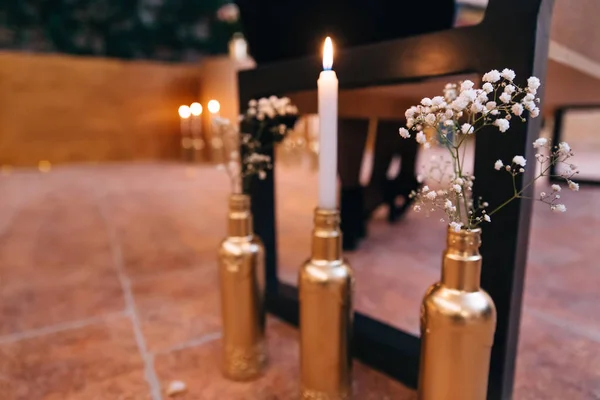 A candle in bottle and branches of white flowers also in bottles — Stock Photo, Image