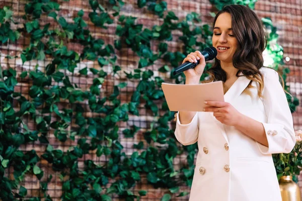 The master of ceremonies reads a speech. woman in a white suit w