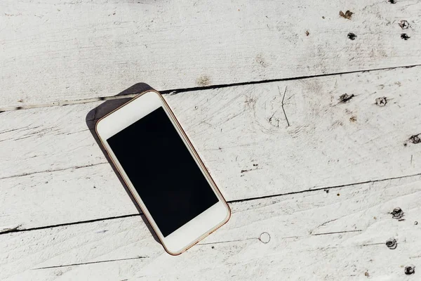 White wooden planks and cellphone with a large screen. close up — 스톡 사진