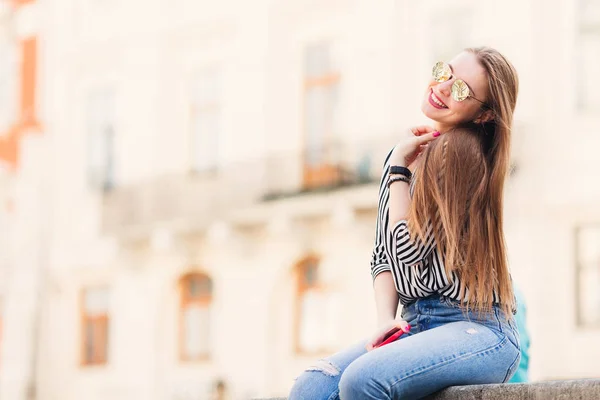 Menina bonita com cabelos longos e óculos de sol sentados nas costas — Fotografia de Stock