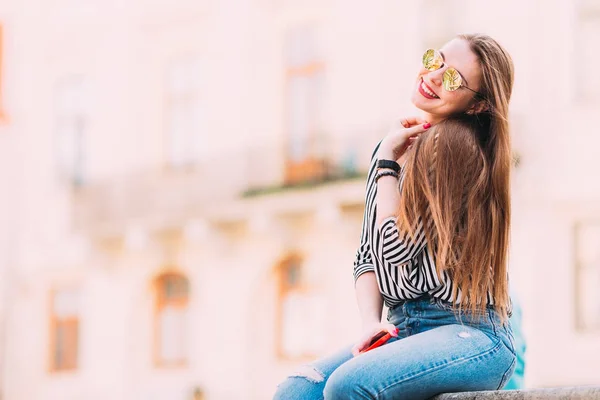 Belle fille avec les cheveux longs et des lunettes de soleil assis sur le dos — Photo