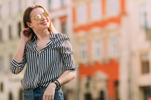Mooie jonge vrouw in zonnebril wandelen in de stad. Glimlach. — Stockfoto