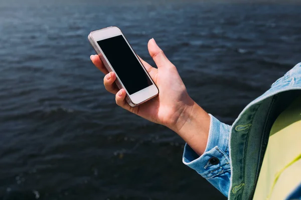 Дівчина тримає мобільний телефон з великим екраном. вода озера — стокове фото
