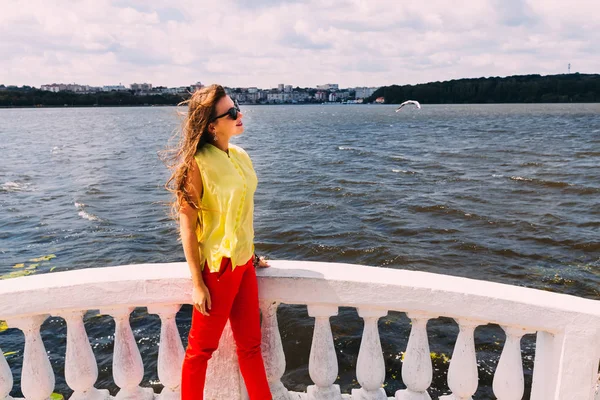 Flicka med solglasögon på bakgrunden av sjön och staden — Stockfoto