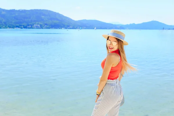 Jovem mulher elegante sorri. lago e montanhas. menina em vidro de sol — Fotografia de Stock