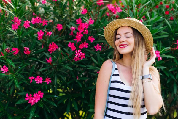 Ein Mädchen neben Sträuchern mit Blumen in einem Bootsfahrer und einem stilvollen Dre — Stockfoto