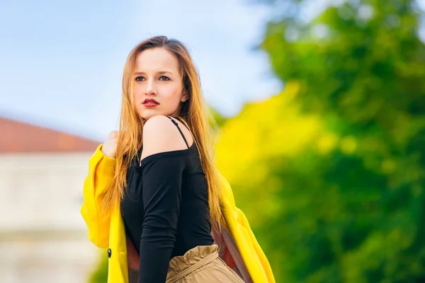 Girl with beautiful makeup poses in black blouse and yellow coat — Stock Photo, Image