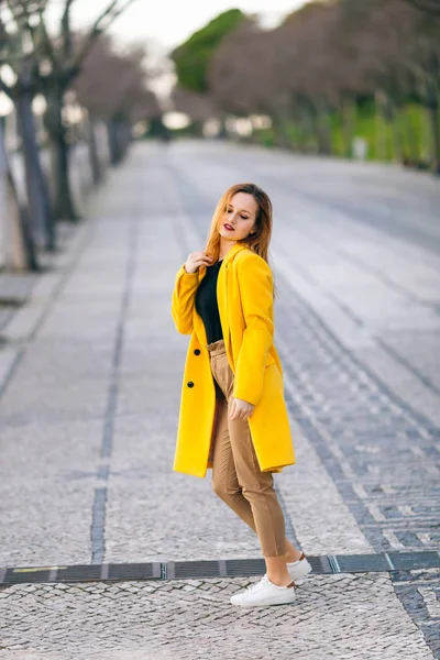 黄色のコートを着た女の子が通りを歩いている姿です。女のファ — ストック写真
