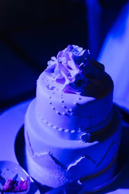 Üç katlı bir düğün pastası krema ile kaplıdır ve w dekore