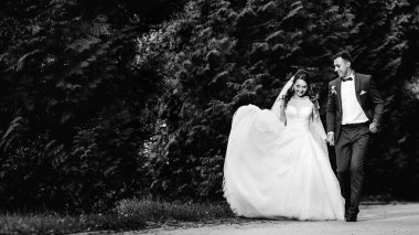 yeni evliler el ele tutuşup parkta siyah beyaz yürürler.