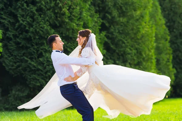 Le marié étreignait la mariée derrière la taille et ils tourbillonnaient — Photo