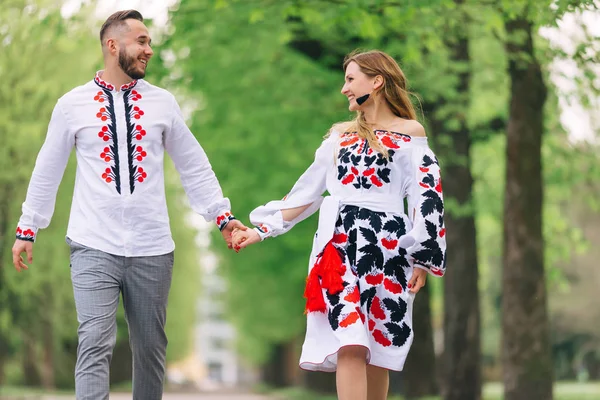 Recién casados tomados de la mano y sonríen. Ropa bordada. caminar en el —  Fotos de Stock