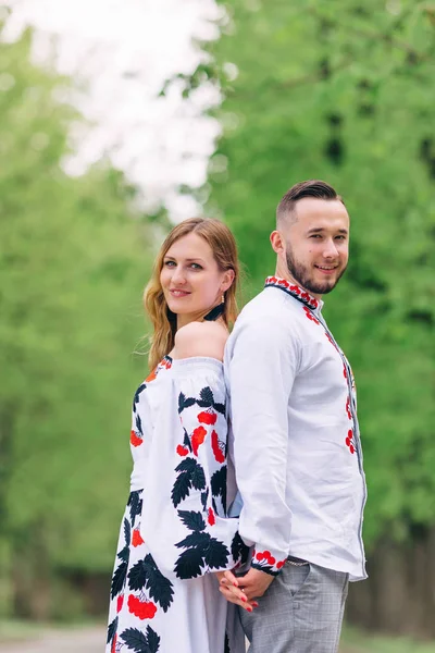 Gli sposi in abiti ricamati stanno schiena contro schiena e sorridono. p — Foto Stock