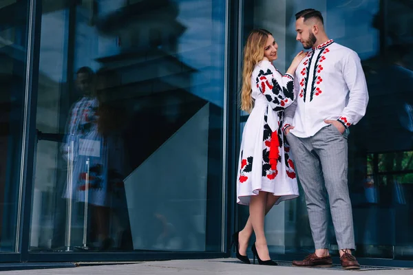 Das Mädchen im bestickten Kleid umarmt den Kerl und blickt ihn an — Stockfoto