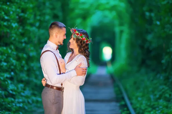 Glückliches verliebtes Paar umarmt und lächelt. Baumtunnel und Eisenbahn. — Stockfoto