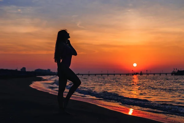 Silhouette eines Mädchens mit schlanker Figur auf dem Hintergrund des Meeres — Stockfoto