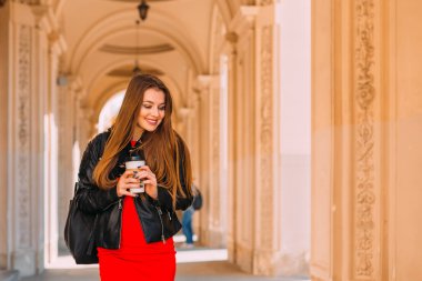 Deri ceket giyen ve elinde elbisesi olan çekici bir kız.