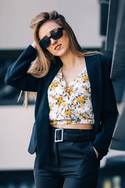 Joven mujer de negocios en gafas de sol y traje en el fondo o — Foto de Stock