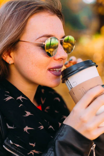 Крупним планом дівчина в сонцезахисних окулярах п'є каву. дівчина з веснянкою — стокове фото
