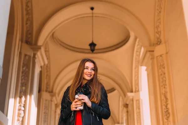 Красивая девушка с длинными волосами в кожаной куртке держит чашку — стоковое фото