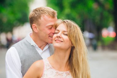 Adam parkta kıza sarılır ve öper. Gülümseme.