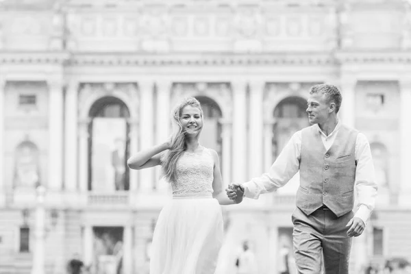 Recién casados tomados de la mano y sonríen. hermosa arquitectura de la bu — Foto de Stock