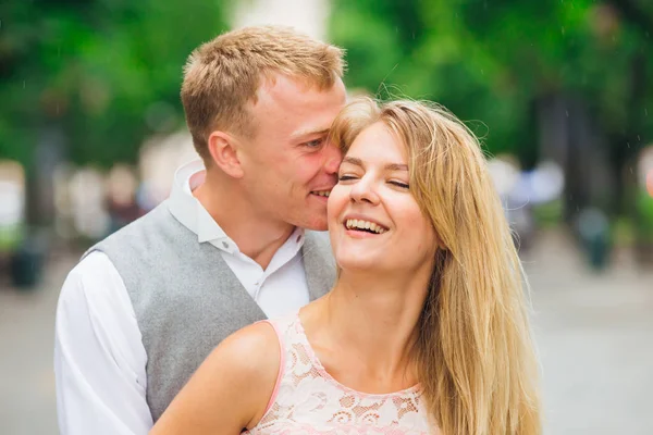 Killen kramar och kysser flickan i parken. Leende. — Stockfoto