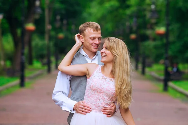 Lo sposo tiene la sposa sulle braccia. guardare la macchina fotografica e sorridere . — Foto Stock