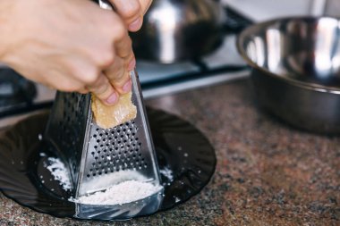 adam parmesan peyniri bir parça tutar ve bir grater üzerinde ovuşturdu. Kiti