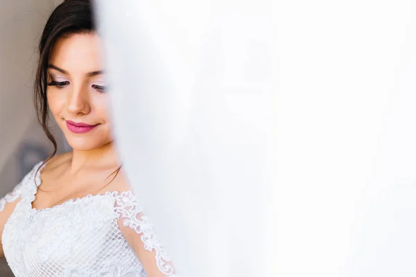 Bride with a beautiful makeup on the background of white curtain — Stock Photo, Image