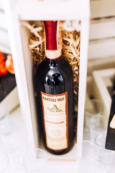 Bottle of red wine dark glass in a wooden stand on the table.